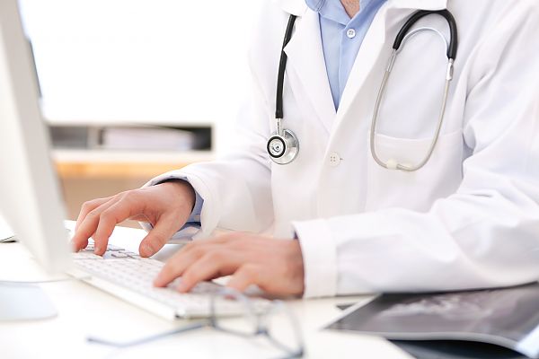 Details of doctor hands typing on keyboard